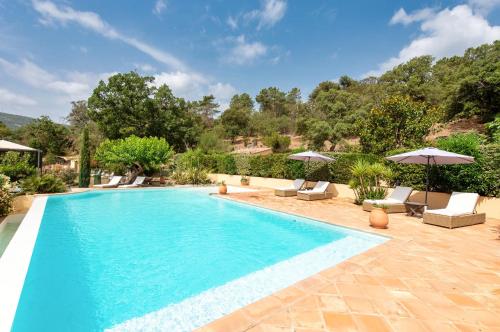 une piscine avec chaises et parasols dans une cour dans l'établissement La Bergerie, au Plan-de-la-Tour