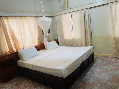 1 dormitorio con 1 cama grande con sábanas blancas en One World Village Guesthouse en Bakau