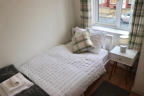 a small bedroom with a bed and a window at Home Away From Home - 2 Bed FREE Parking & Wifi in Hunslet