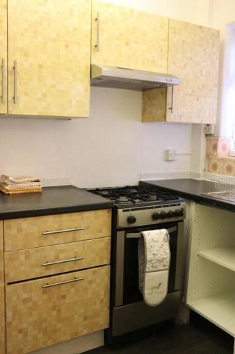 a kitchen with a stove and wooden cabinets at Home Away From Home - 2 Bed FREE Parking & Wifi in Hunslet