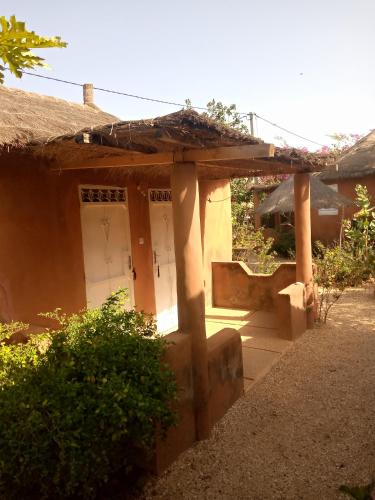 a small house with a white door in a yard at Campement Baobab chambres d'hotes 15mn de l'aeroport in Poponguine