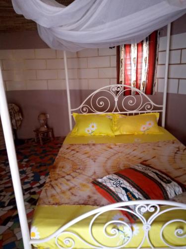 a bed with a canopy in a room at Campement Baobab chambres d'hotes 15mn de l'aeroport in Poponguine