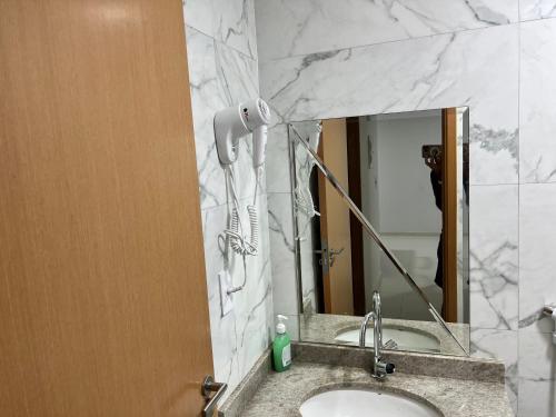 a bathroom sink with a blow dryer on a mirror at PORTO CAYMAN RESIDENCE - BEIRA MAR - próximo a Igreja de São Pedro de Padre Arlindo - in Tamandaré