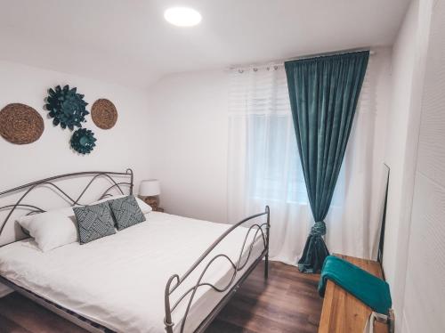 a bedroom with a bed and a green curtain at Villa-Apartments Bognar in Velika