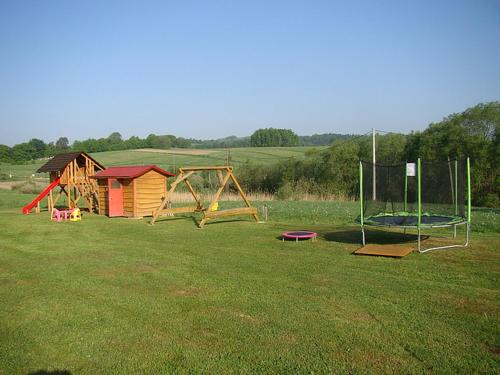 a park with a playground and a house in a field at Rancho Zawóz domek nr5 in Zawóz