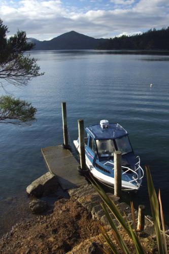 a small boat parked at a dock on a lake at Hopewell Lodge in Kenepuru Sounds