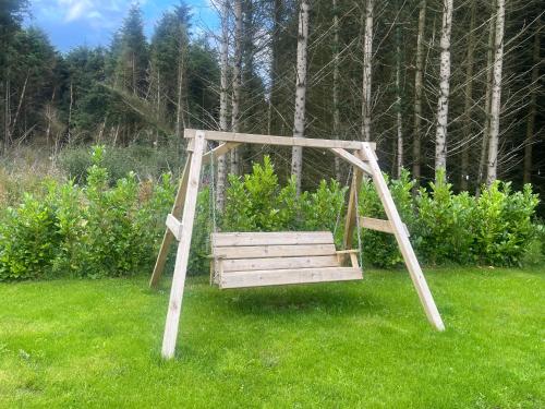 a wooden swing in the grass in a yard at Woodland lodge, apartment in Derry Londonderry