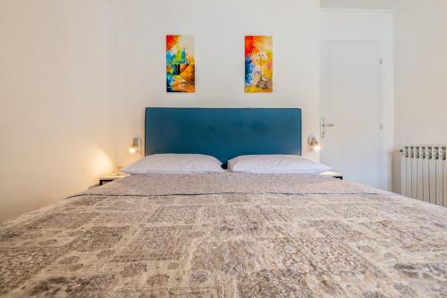 a large bed with a blue headboard and two pillows at Apartments Sentic in Neum