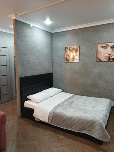 1 dormitorio con 1 cama con 2 cuadros en la pared en Квартира бизнес -класса в ста метрах от городского парка, en Petropavlovsk