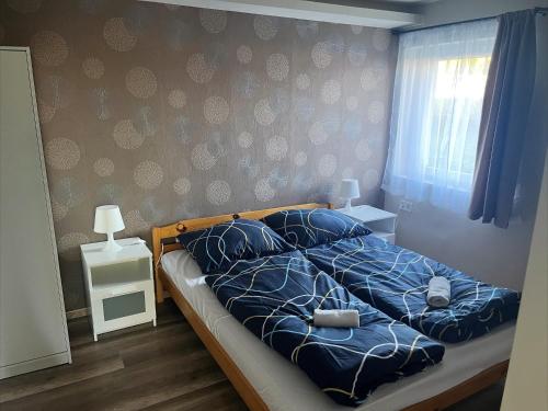a bedroom with a bed with blue comforter and a window at Zöldház Panzió in Gyenesdiás