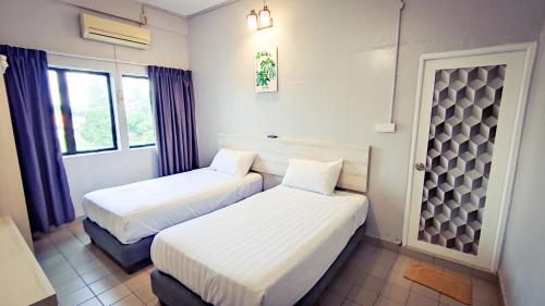 two beds in a room with two windows at Lotus Inn in Melaka
