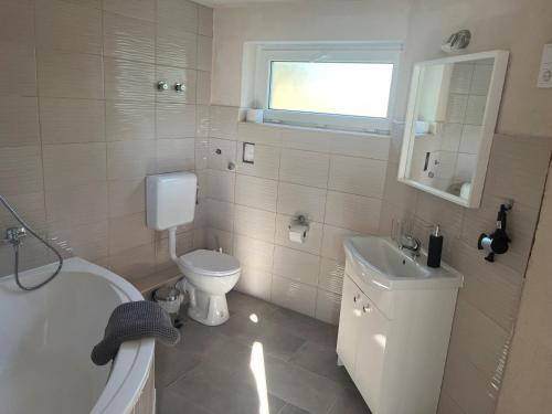a white bathroom with a toilet and a sink at Zöldház Panzió in Gyenesdiás
