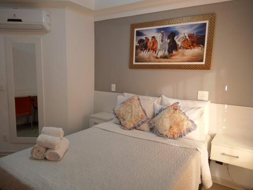 a bedroom with a white bed with a picture on the wall at Studio Aconchego, próximo a Rua da Consolação, aos Metros República e Anhangabaú, com ar condicionado, piscina, academia, wifi e varanda in Sao Paulo