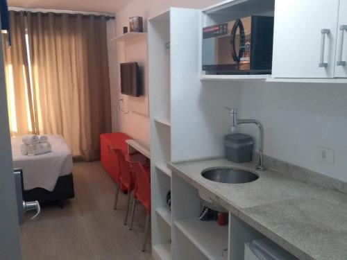 a kitchen with a sink and a room with a bed at Studio Aconchego, próximo a Rua da Consolação, aos Metros República e Anhangabaú, com ar condicionado, piscina, academia, wifi e varanda in Sao Paulo