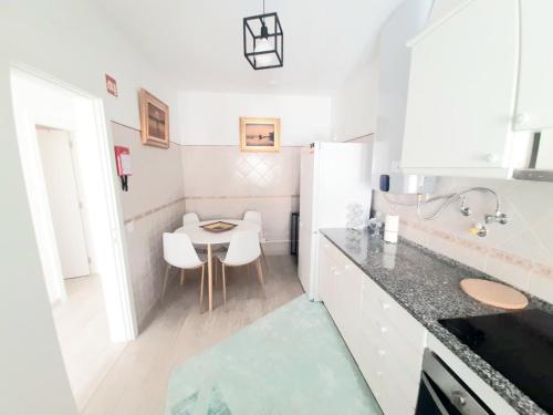 - une petite cuisine avec une table et des placards blancs dans l'établissement Alojamento local "CASA BRANCA", à Albufeira