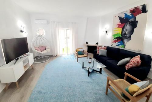 a living room with a black couch and a tv at Alojamento local "CASA BRANCA" in Albufeira