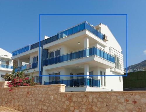 a white building with blue balconies on top of a wall at Penthouse duplex "il GiraSole suite" in Kalkan