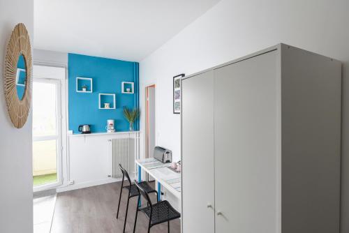 Cette chambre est dotée d'un bureau, de chaises et d'un mur bleu. dans l'établissement Superbe 2 pièces - proche de Paris, à Villeneuve-la-Garenne