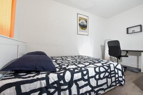 Schlafzimmer mit einem Bett, einem Schreibtisch und einem Stuhl in der Unterkunft Superbe 2 pièces - proche de Paris in Villeneuve-la-Garenne