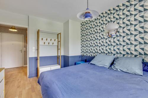 een slaapkamer met een blauw bed en een grote muur bij Le Saint Cyr in Saint-Cyr-lʼÉcole