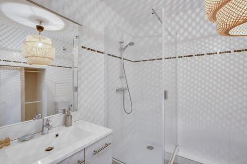 Un baño blanco con ducha y lavabo. en Le Saint Cyr, en Saint-Cyr-lʼÉcole