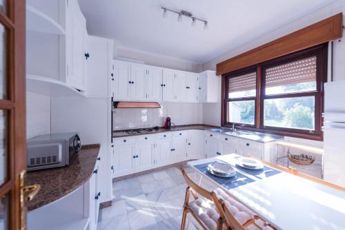 una cocina con armarios blancos y una mesa con sillas. en Luminoso apartamento reformado en villa termal, en Cuntis