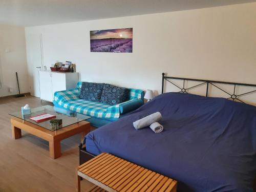 1 dormitorio con 1 cama azul y 1 sofá en Maison d'hôtes Bleu Cudrefin, en Cudrefin