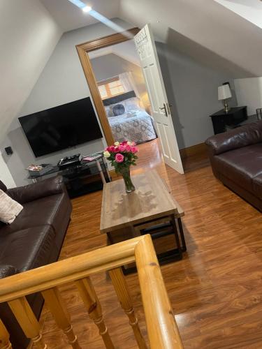 sala de estar con sofá y mesa con flores. en Woodland lodge, apartment, en Derry Londonderry