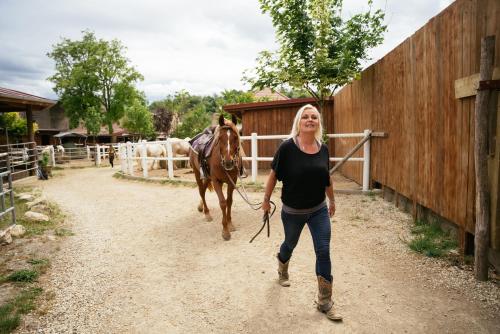 a woman walking a horse down a dirt road at Ranchzimmer am Hippo-Campus Reit- und Therapiezentrum in Deutsch Haslau