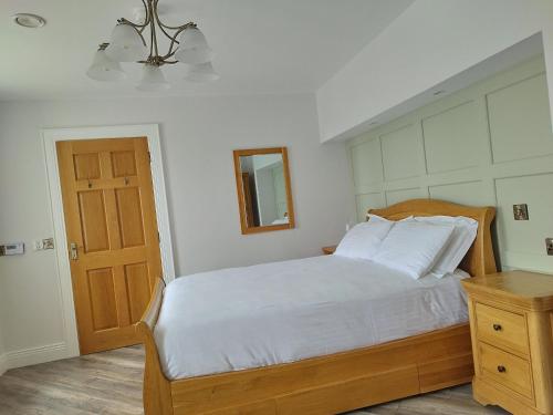 a bedroom with a bed with white sheets and a mirror at Biddy Ban’s in Carnmalin