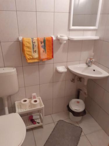 a white bathroom with a sink and a toilet at Margit kulcsosház in Rareş
