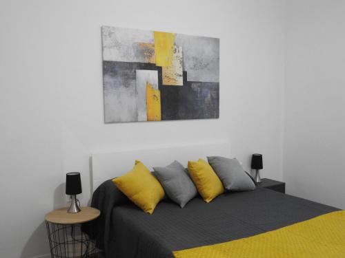 sypialnia z łóżkiem z żółtymi i szarymi poduszkami w obiekcie Precioso apartamento con sauna y terraza w mieście Bas