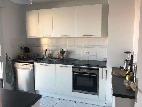 a kitchen with white cabinets and black counter tops at Chambre dans appartement avec vue sur le port in Lattes