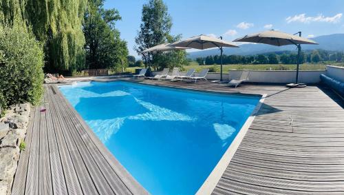 a swimming pool with a wooden deck and umbrellas at Domaine La Reveille in Dore-lʼÉglise