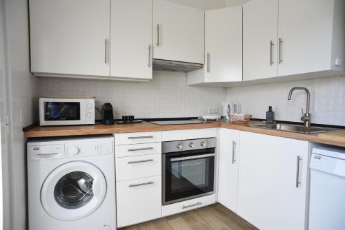 a white kitchen with a washing machine and a microwave at NiaAzoreanApartments2, aconchegante e confortável! in Horta