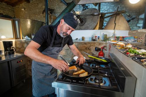 a man cooking food in a pan on a stove at Aqua Et Oleum in Villamiel