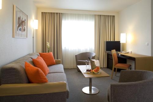 a living room with a couch and a desk in a hotel room at Novotel Belfort Centre Atria in Belfort