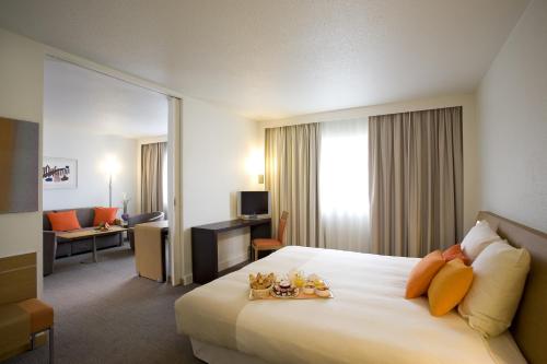 a hotel room with a bed and a living room at Novotel Belfort Centre Atria in Belfort