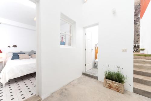 1 dormitorio con paredes blancas, 1 cama y una escalera en Casita tradicional canaria en Garachico - SanRoquito18, en Garachico