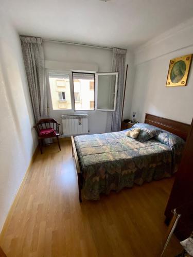 een slaapkamer met een bed, een stoel en een raam bij APARTAMENTO CENTRO BURGOS in Burgos