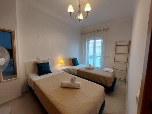 a room with two beds with a chandelier at Encosta do Sol Apartamentos in Albufeira