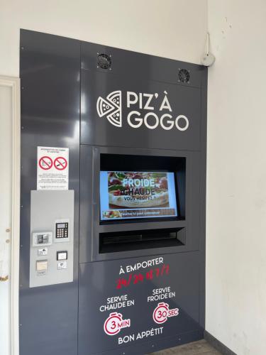 a pizzaoco machine with a tv in a building at Hôtel du Commerce in Semur-en-Auxois