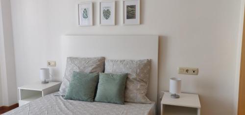 Dormitorio blanco con cama con almohadas verdes en Apartamento en Canet Playa con Parking y WIFI, en Canet de Berenguer