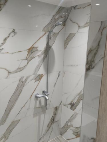 a shower with white marble tile and a shower facet at Capital Apartment kilkis in Kilkis