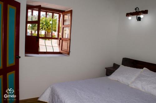 a bedroom with a bed and a window at HOTEL COLONIAL VILLA CARMELA in Tota