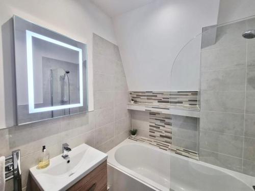 a white bathroom with a sink and a bath tub at Lovely 1 Bed Apartment in Old Market Square in Nottingham