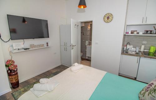 a white room with a bed and a tv on the wall at Apartman Sarah Mostar in Mostar