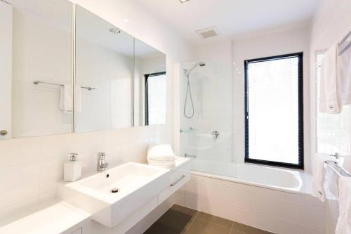 a white bathroom with a sink and a bath tub at Luxurious, Tranquil and Private in Lindisfarne