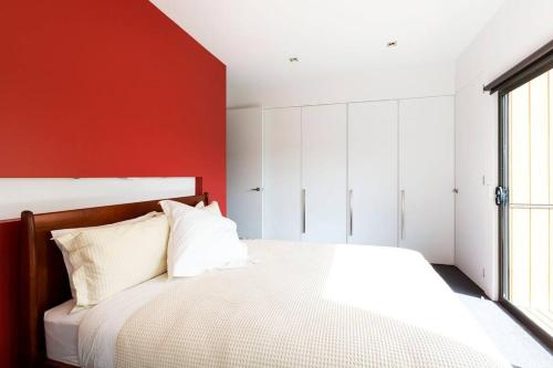 a bedroom with a white bed and a red wall at Luxurious, Tranquil and Private in Lindisfarne