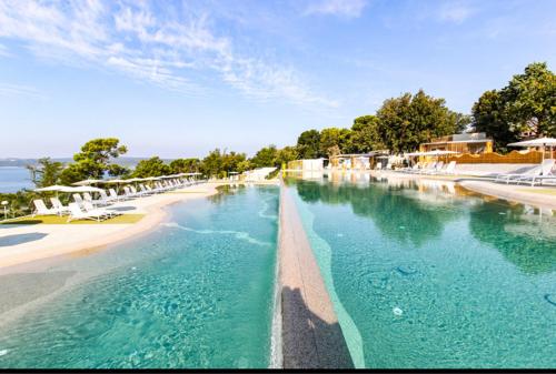 una piscina de agua azul junto a una playa en Villa Family Grand de Luxe Mobilhome en Selce